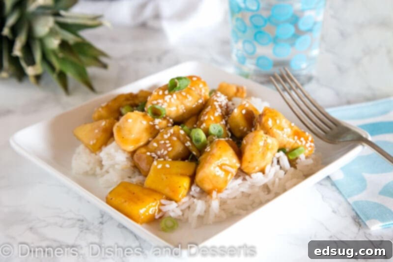 Tropical Pineapple Teriyaki Chicken 5 A top-down view of a plate of Pineapple Chicken Teriyaki, garnished with green onions and sesame seeds, alongside a bowl of white rice.