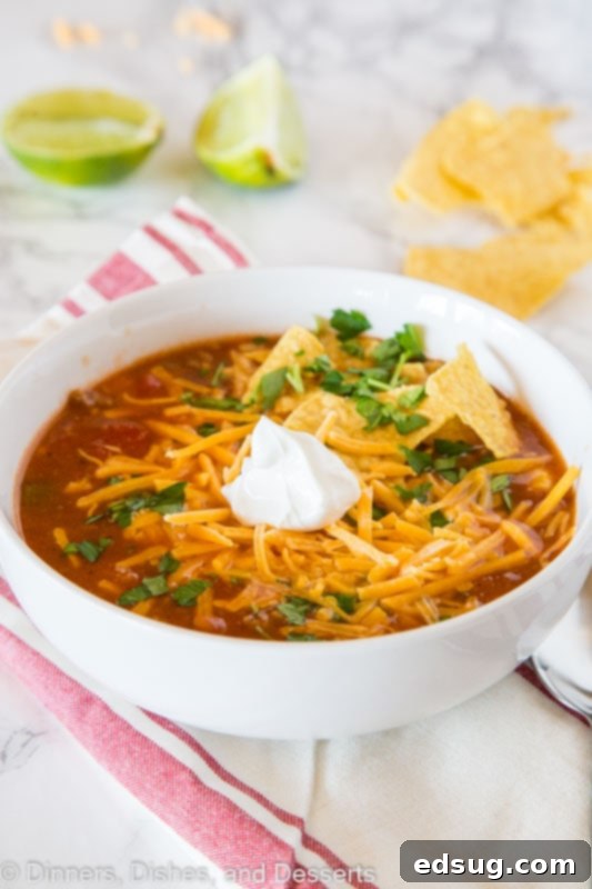 A steaming bowl of hearty taco soup garnished with fresh toppings