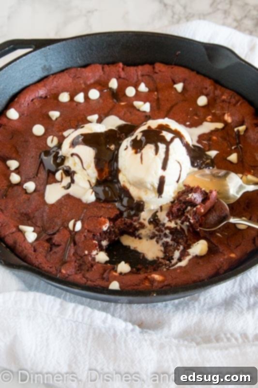 Decadent Red Velvet Skillet Cookie 2 Warm Red Velvet Skillet Cookie topped with melting vanilla ice cream and hot fudge, served in a cast iron skillet with a spoon