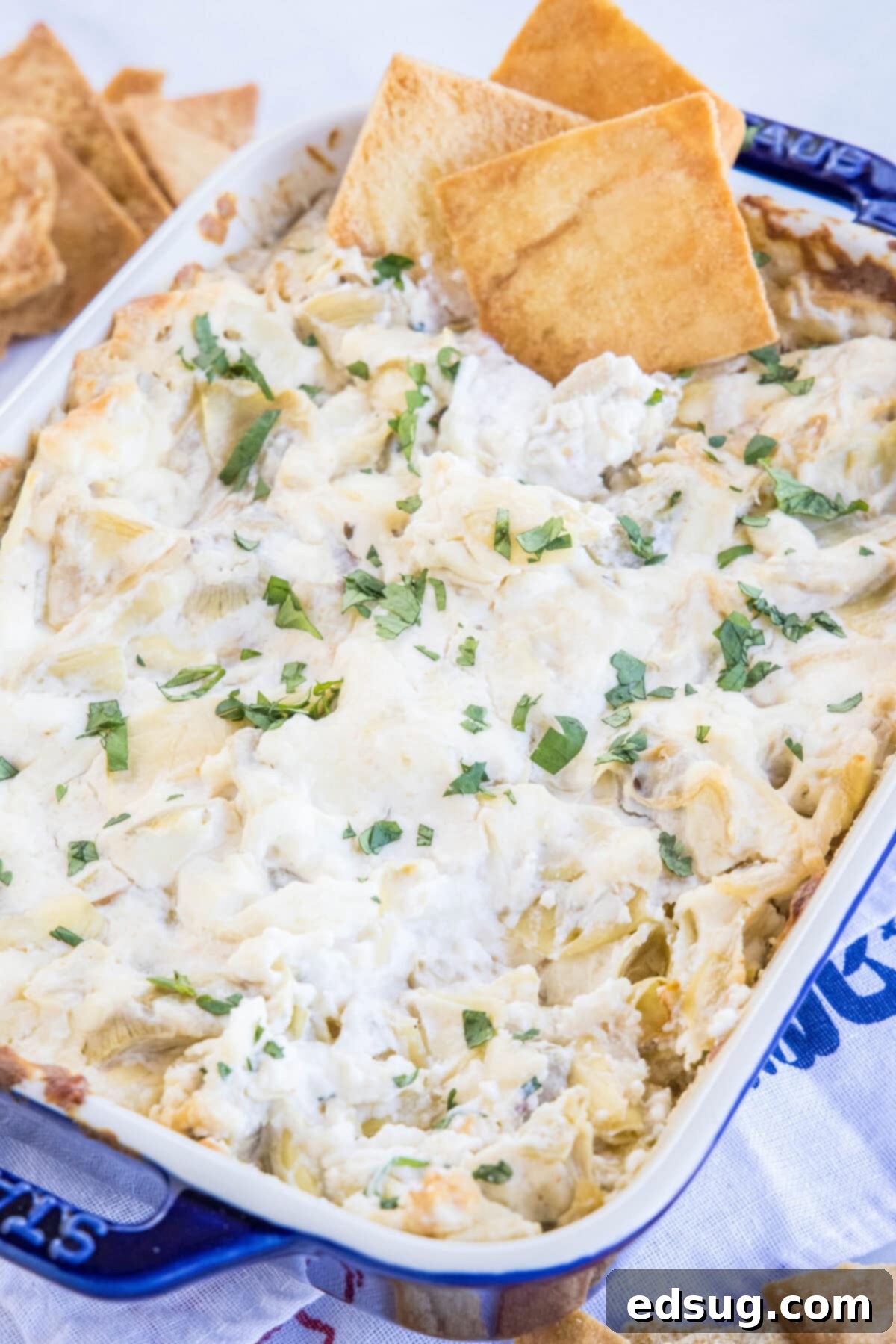 Baked cheesy artichoke dip in a baking dish, golden and bubbly.