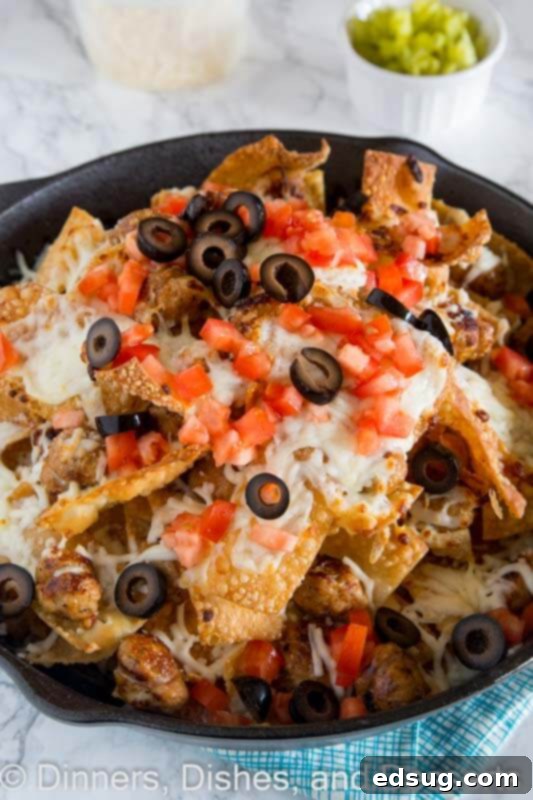 A vibrant bowl of Italian nachos topped with melted cheese, chicken sausage, and fresh herbs, ready to be served as an appetizer.