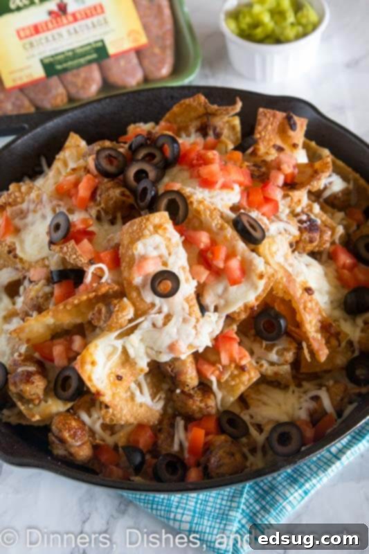 A close-up shot of a ceramic bowl filled with golden Italian nachos, featuring crispy wonton chips, Italian chicken sausage, and gooey melted cheese, garnished with fresh toppings.