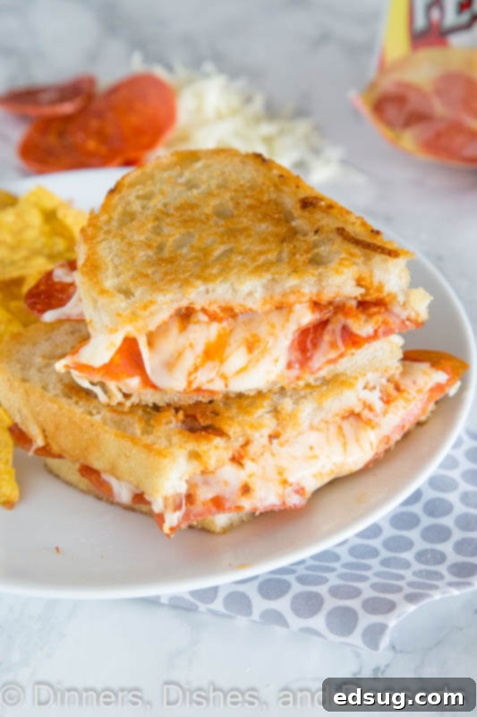 Pepperoni pizza grilled cheese cut in half, stacked on a plate