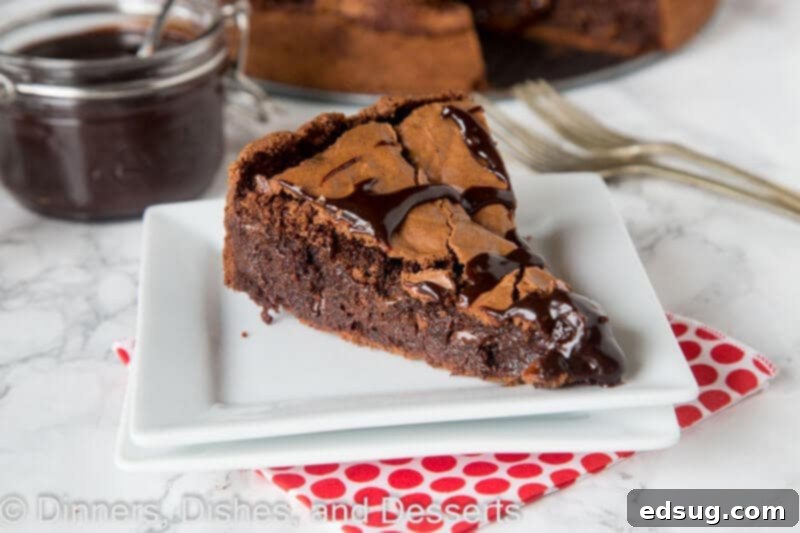 Deep Dish Fudgy Brownie 4 A delectable slice of Gooey Brownie Pie, topped with rich hot fudge, presented on a plate, ready to be devoured.