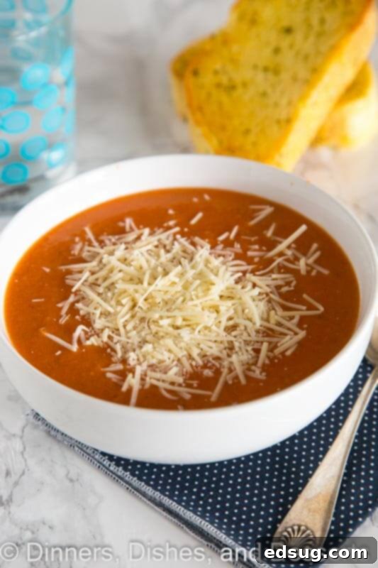Creamy tomato soup in a rustic bowl, garnished with a sprig of fresh basil, against a cozy backdrop.