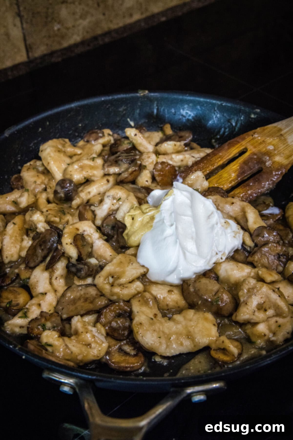 Velvety Chicken Stroganoff 4 Adding sour cream and Dijon mustard to the chicken and mushroom mixture in a skillet to create the creamy stroganoff sauce