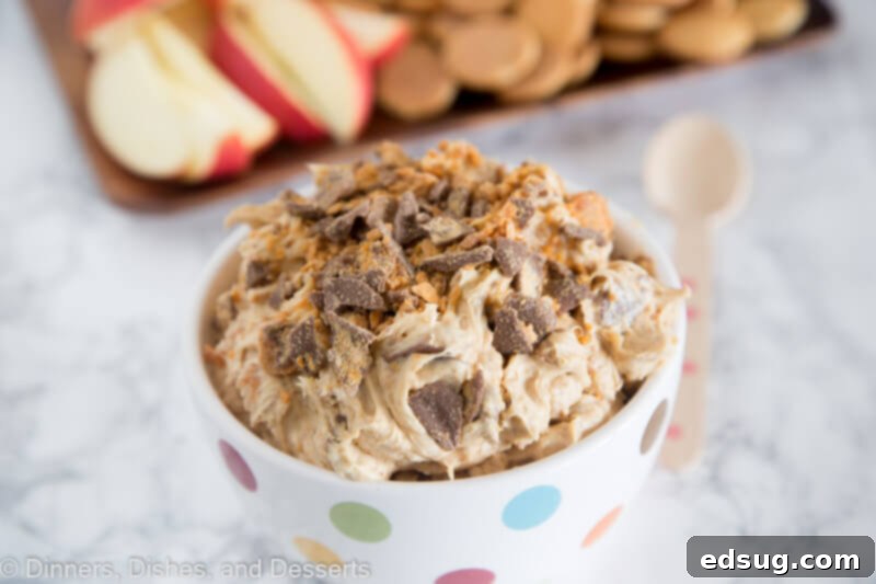 A scoop of peanut butter Butterfinger dip with a hint of apple slices