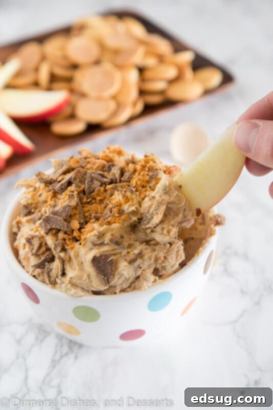 Bowl of Peanut Butter Butterfinger dip served with fresh apple slices