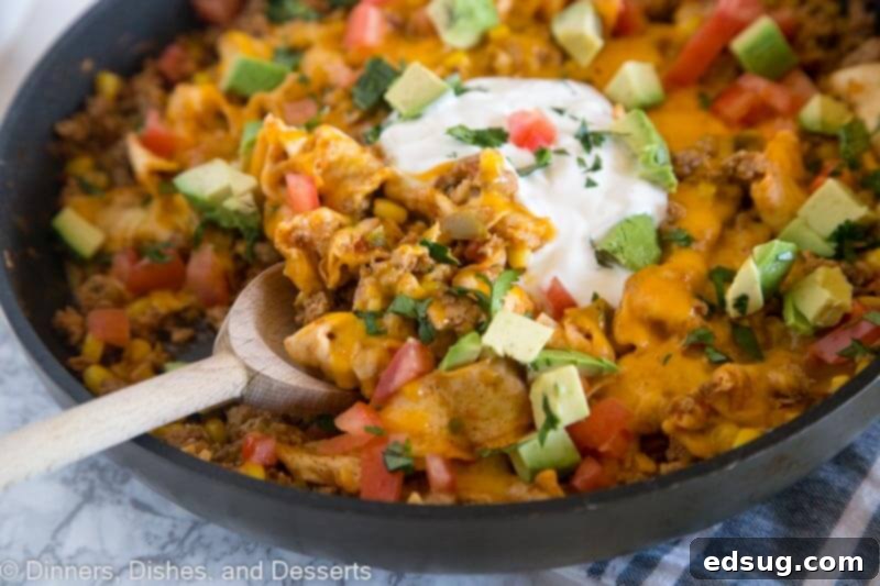 A skillet with beef burrito skillet and a serving spoon, showcasing the delicious meal.