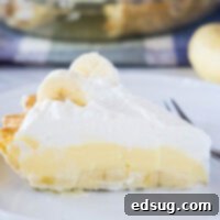 Close up of a slice of banana cream pie on a plate with a fork