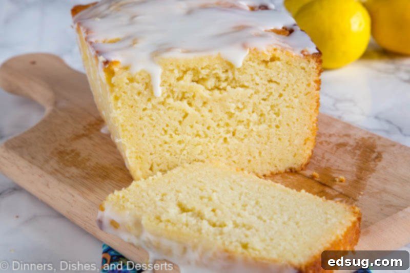 Sunshine Lemon Ricotta Loaf 3 A delectable slice of lemon ricotta pound cake, showcasing its moist interior and a generous drizzle of lemon glaze, resting on a wooden cutting board.