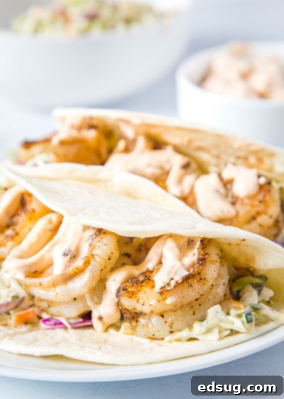 Plated Baja Shrimp Tacos with fresh avocado slices and a creamy drizzle