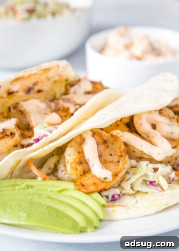 Finished shrimp tacos beautifully arranged on a plate with sliced avocado
