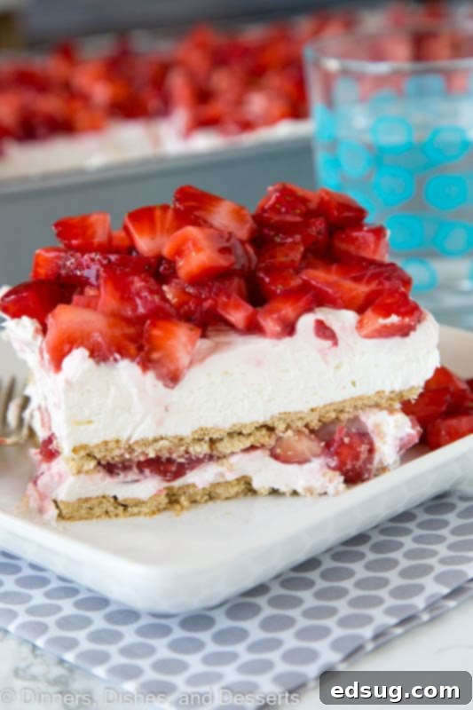 Sweet Layers of Strawberry Cheesecake Bliss 2 A slice of strawberry cheesecake lasagna on a white plate with fresh strawberries and a fork, showcasing the layers