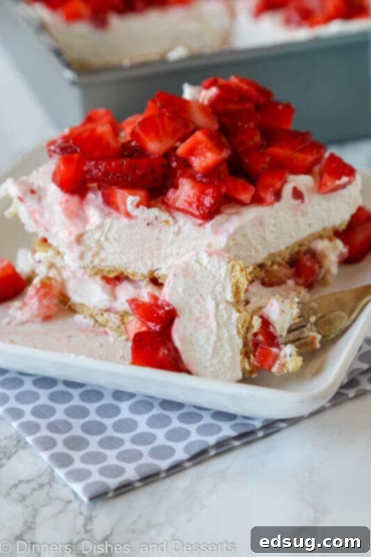 Sweet Layers of Strawberry Cheesecake Bliss 3 A close-up of strawberry cheesecake lasagna with a fork, highlighting the creamy layers and diced strawberries