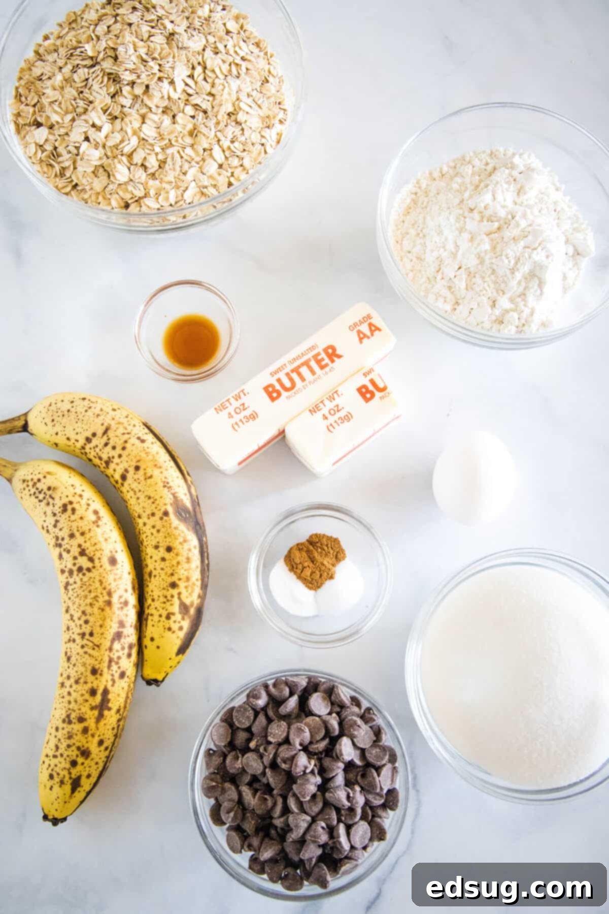 Ingredients laid out for banana chocolate chip cookies, including butter, sugar, bananas, oats, flour, and chocolate chips
