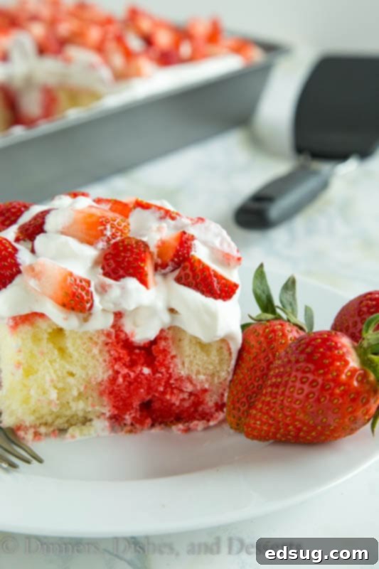 Strawberry poke cake topped with fresh strawberries and fresh whipped cream