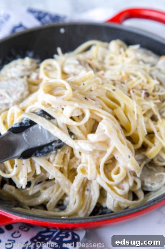 Indulgent Chicken Sausage Alfredo 2 A skillet of pasta with sauce and cheese, with chicken sausage and Fettuccine Alfredo