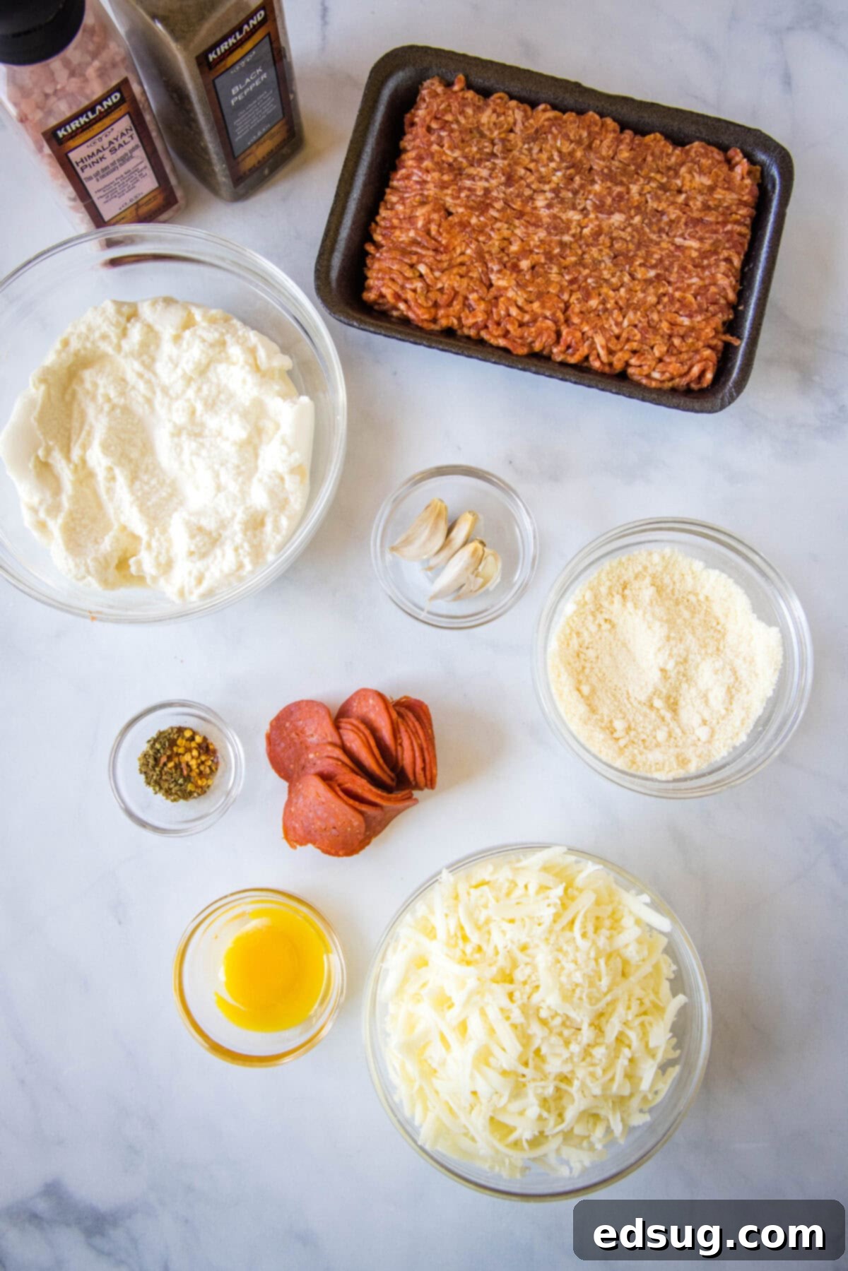 Folded Pizza Pockets 3 Various ingredients for calzones laid out on a wooden board, including cheese, sausage, pepperoni, and fresh herbs.