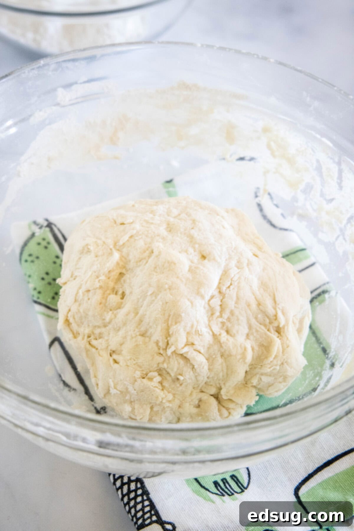 Folded Pizza Pockets 5 Pita dough in a glass bowl, showcasing a smooth, proofed texture.