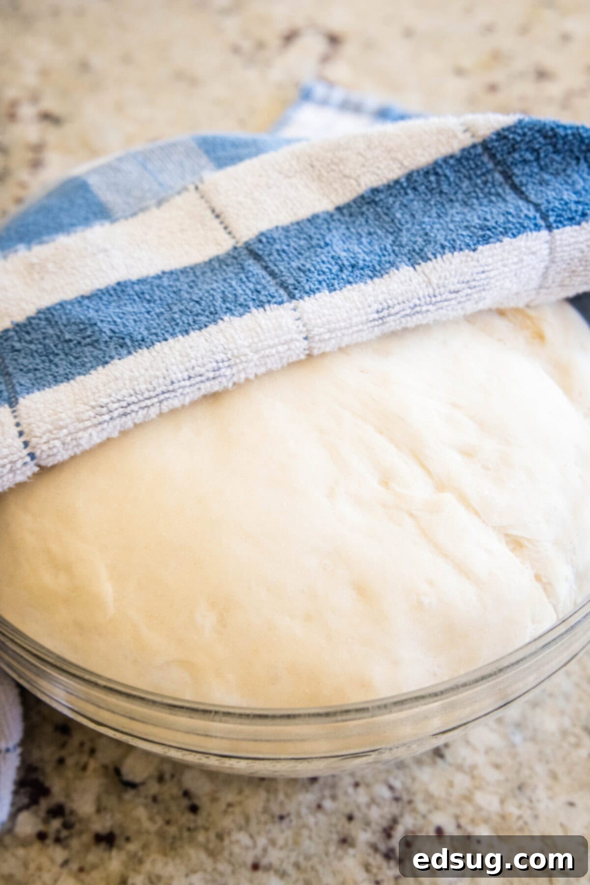 Folded Pizza Pockets 6 Bread dough rising in a mixing bowl, covered, showing increased volume.