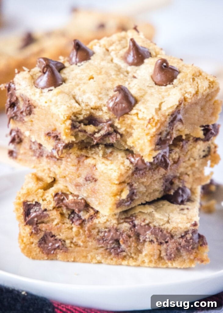Ultimate Peanut Butter Chocolate Chip Bars 2 Stack of freshly baked, chewy peanut butter chocolate chip bars, with one showing a delicious bite taken out