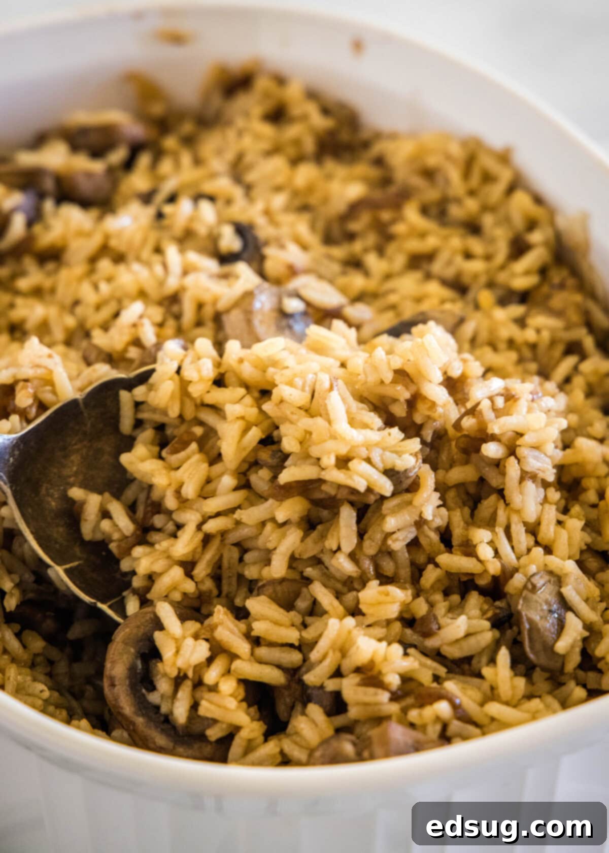 scooping stick of butter rice out of baking pan