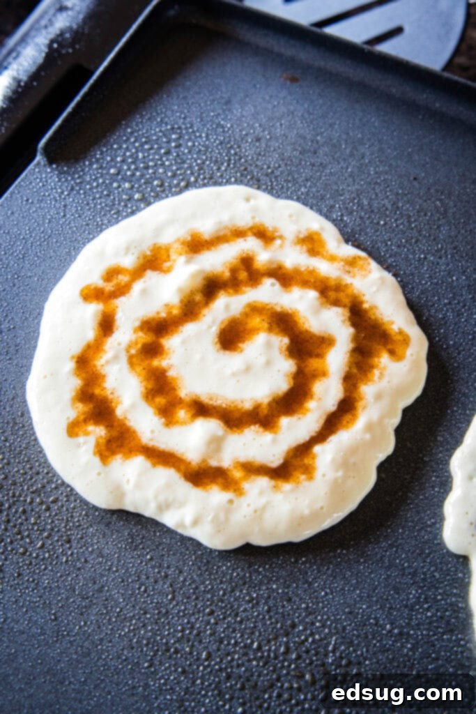 Cinnamon Swirl Pancakes 3 pancake on griddle with cinnamon swirl