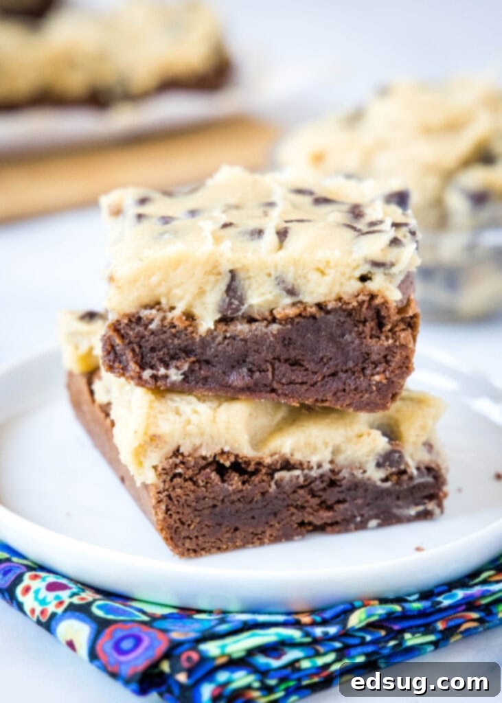 Stacked brownies generously frosted with edible cookie dough frosting on a white plate, showcasing a rich and inviting dessert.