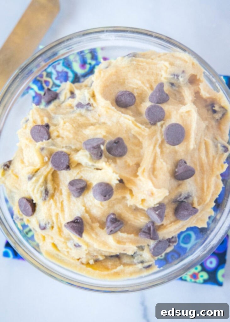 Overhead view of a glass bowl filled with freshly made, creamy cookie dough frosting, studded with chocolate chips, ready to be used as a spread or dip.