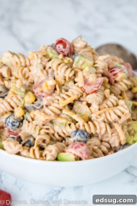 A vibrant bowl of creamy taco pasta salad with colorful ingredients ready to be served at a summer gathering.