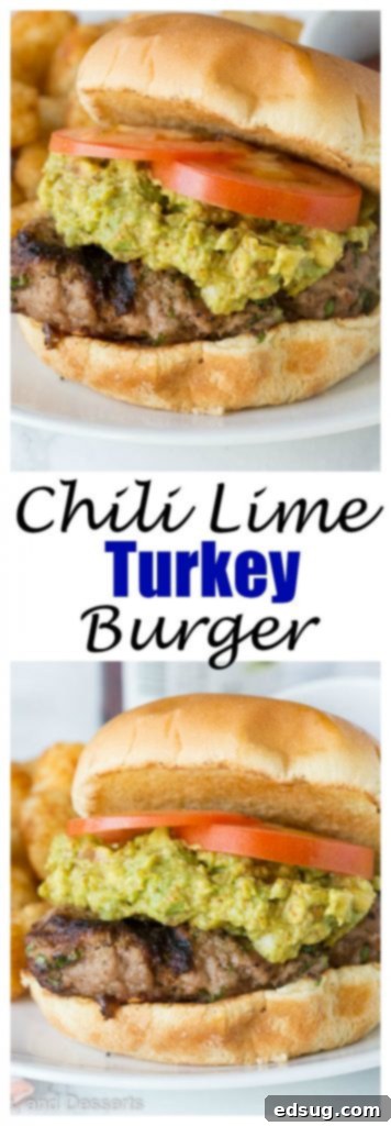 A side view of a chili lime turkey burger, adorned with guacamole and a tomato slice, on a white plate.