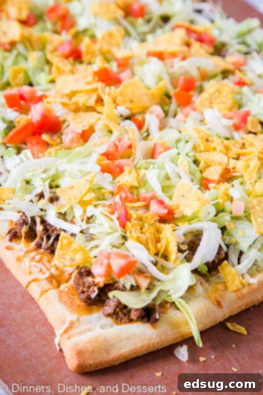 Tex-Mex Pizza 4 Delicious Taco pizza generously topped with refried beans, taco sauce, seasoned taco meat, melted cheese, fresh lettuce, juicy tomatoes, and crunchy tortilla chips!
