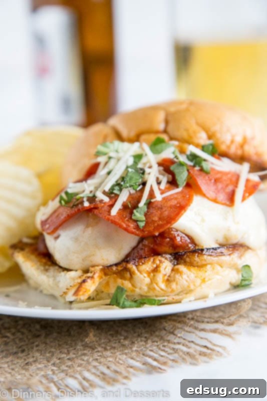 Pepperoni Pizzaburger 2 A close-up view of a delicious pepperoni pizza burger on a plate with potato chips, ready to be enjoyed.