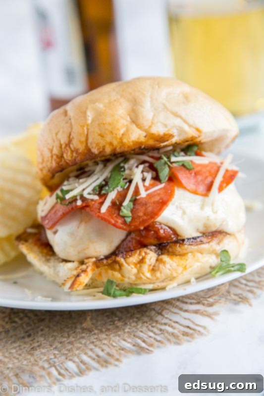 Pepperoni Pizzaburger 5 A serving of pepperoni pizza burger with potato chips, showing the delicious melted cheese and pepperoni, ready to eat.