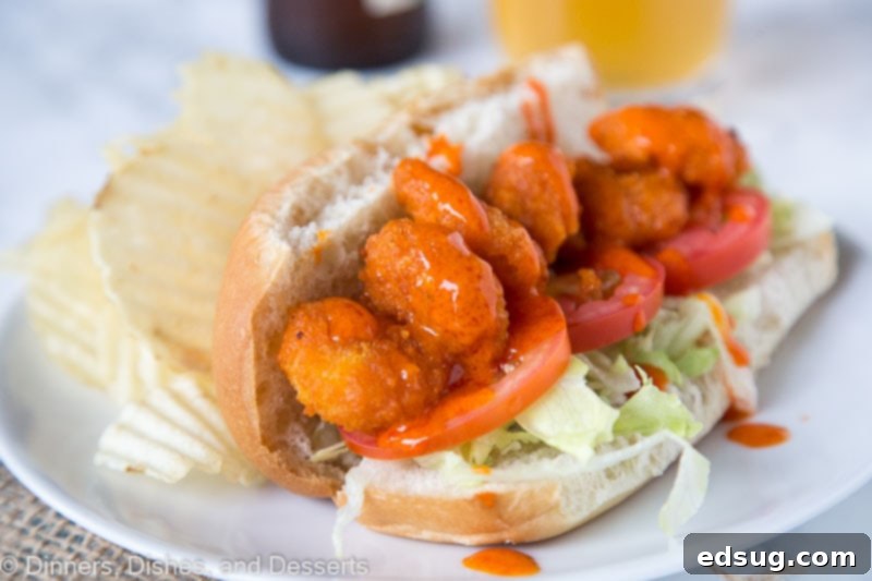 A second view of a generous Buffalo Shrimp Po' Boy, with the crispy shrimp peeking out, accompanied by ranch dressing on a patterned table, highlighting the sandwich's inviting texture.