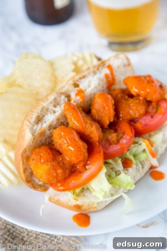 A close-up of a large serving of perfectly cooked buffalo shrimp, glistening with spicy sauce, arranged artfully on a plate, showcasing their inviting color and texture, ready to be added to the Po' Boy.