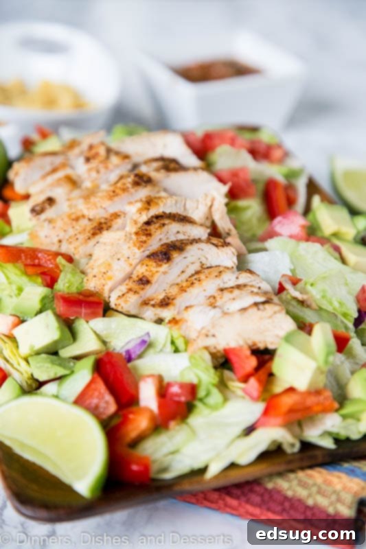 A vibrant Chicken Fajita Salad featuring grilled chicken, colorful peppers, onions, and fresh avocado, drizzled with a salsa vinaigrette.