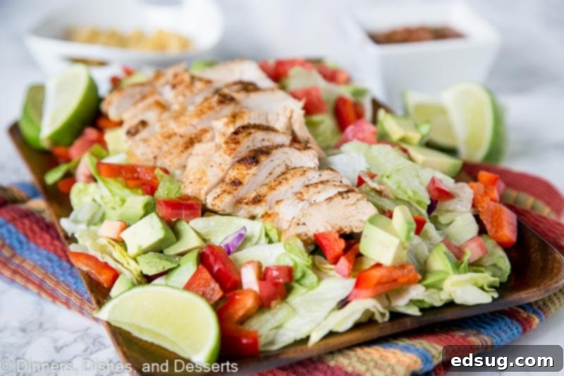 Close-up of a generously topped Chicken Fajita Salad with grilled chicken, peppers, onions, corn, black beans, and a creamy dressing.