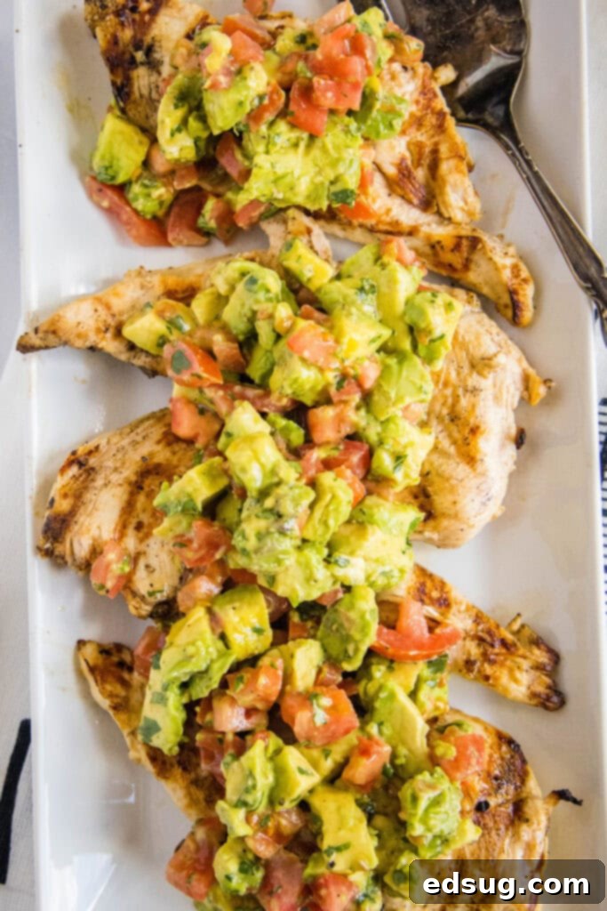 Grilled chicken breasts topped with a generous serving of vibrant avocado and tomato salsa, garnished with fresh cilantro.