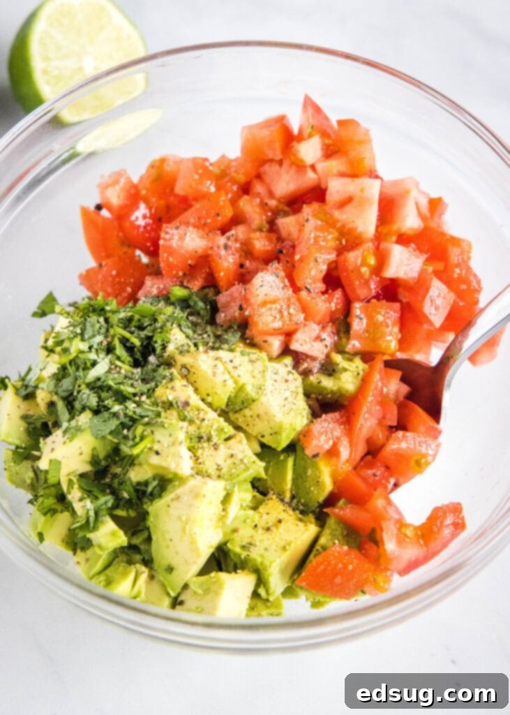 Freshly diced avocado, tomatoes, red onion, and cilantro mixed in a bowl, ready for the salsa.