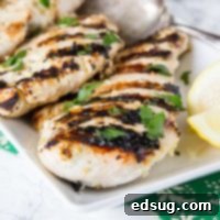 Perfectly Tender Yogurt Chicken 7 Grilled chicken on a plate with lemon slices and parsley garnish, highlighting a delicious meal.