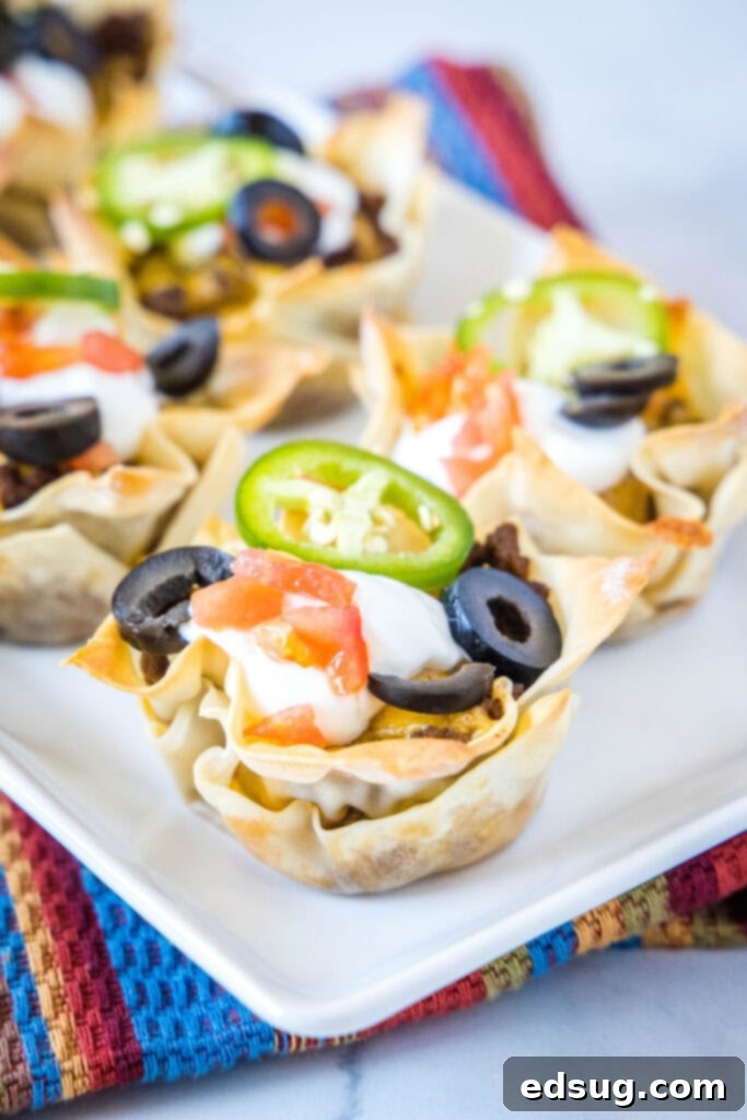Crispy taco cups arranged on a vibrant serving platter, beautifully topped with fresh sour cream and bright red diced tomatoes, ready to be enjoyed as an appetizer.