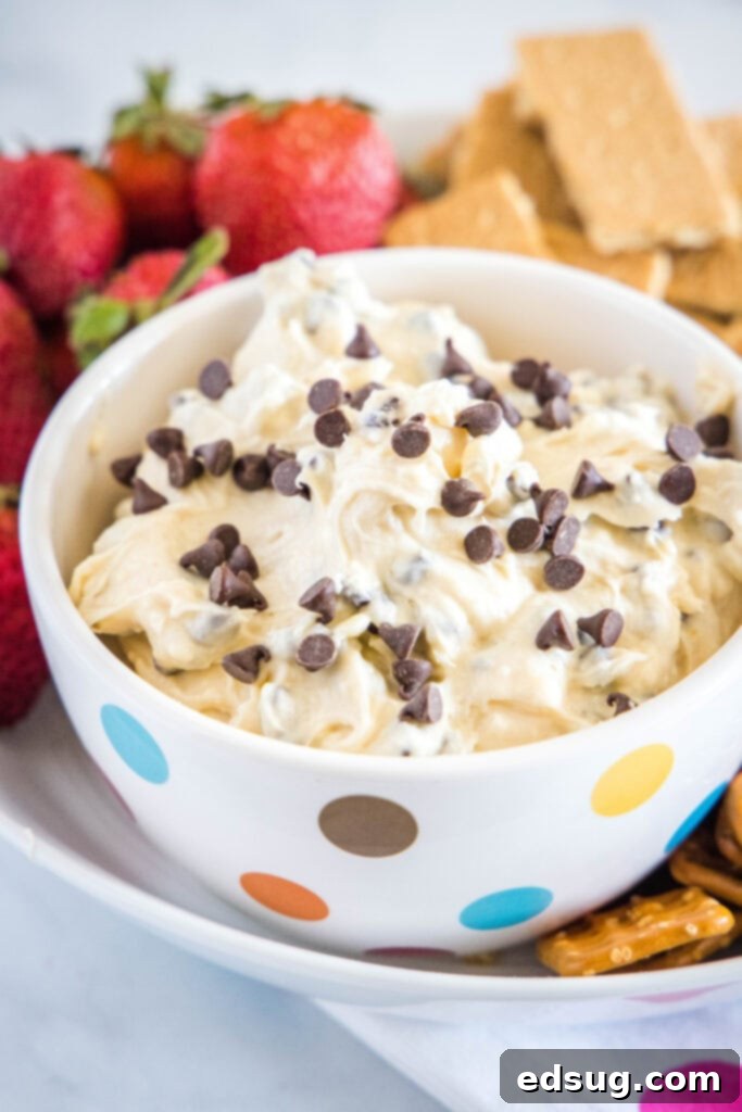 bowl of cookie dough dip with strawberries and graham crakers around it