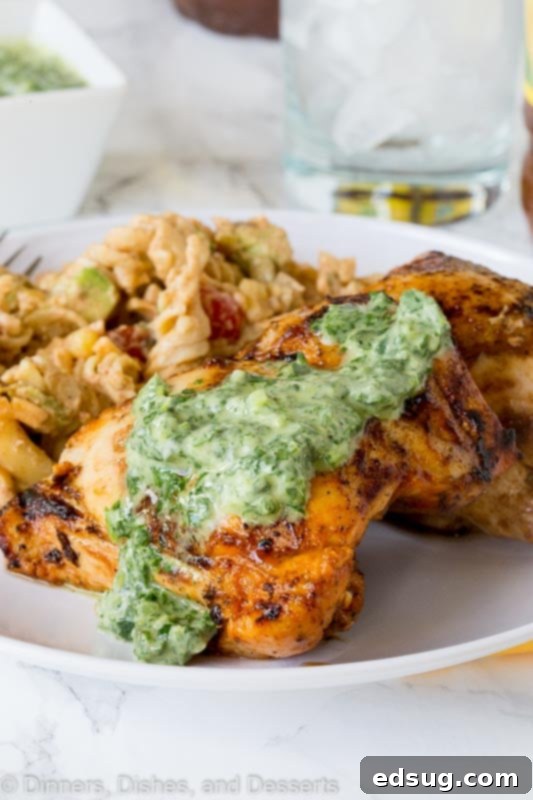 Chargrilled Chicken Thighs 5 A close-up of a plate with grilled chicken and a ramekin of chile herb sauce, showcasing the texture and vibrant colors of the dish.