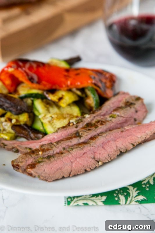 A delicious grilled flank steak sandwich, showcasing tender slices of meat nestled between bread with fresh vegetables and sauce, highlighting its versatility.