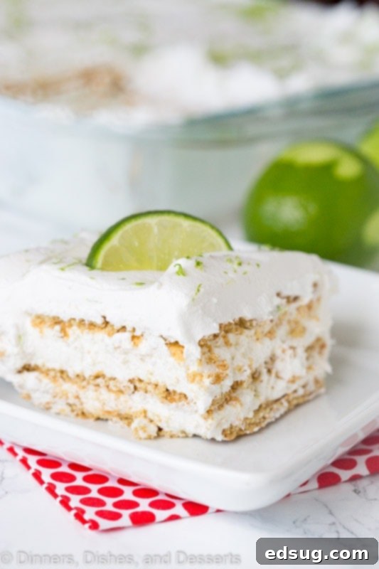 A slice of key lime icebox cake on a plate with fresh lime wedges in the background