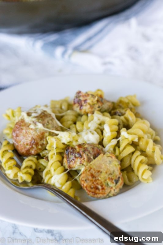 Overhead shot of a full plate of pesto pasta with meatballs, ready to be enjoyed.
