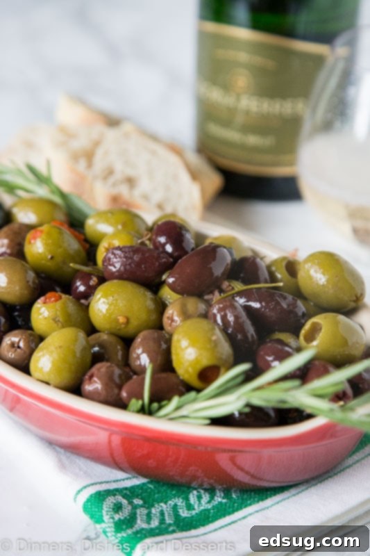 A beautiful bowl of roasted olives garnished with fresh rosemary sprigs, perfect for an appetizer.