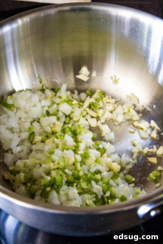 Onions, garlic, and jalapeños are gently sautéing in a pot, releasing their aromatic flavors.